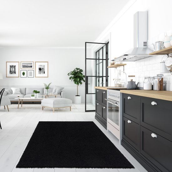 Tapis shaggy noir à poils longs dans une cuisine moderne avec des armoires et un comptoir noirs.