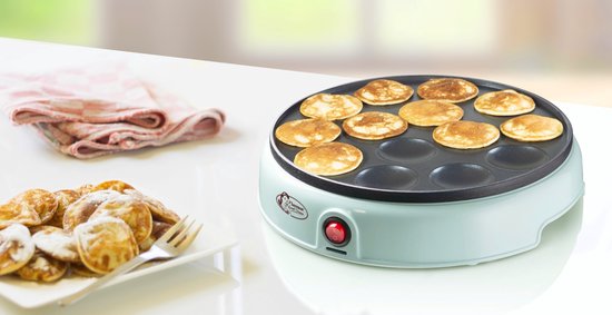 Lichtgroene poffertjespan met 12 goudbruine poffertjes, naast een bord met poedersuiker bestoven poffertjes.
