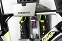 Zilverkleurig Stasdock-rek met zwarte racefietsschoenen, racefietsbril en CO2-patronen, op een racefiets.