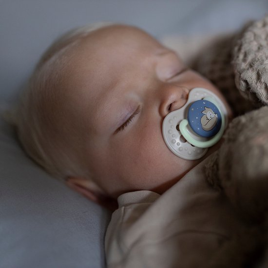 Slapende baby met blonde haren met een beige Difrax lovi fopspeen met vosje die oplicht in het donker.