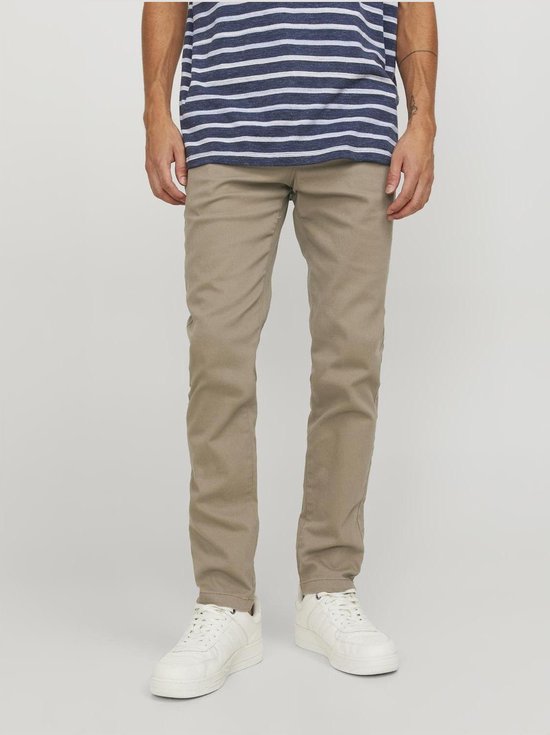 Onderlichaam van een man met gestreept blauw-wit T-shirt en beige chino broek.