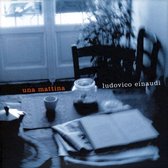 Couverture de CD : "una mattina" en lettres rouges, "ludovico einaudi" en lettres blanches. Une table avec journaux, tasse, pot et cafetière.
