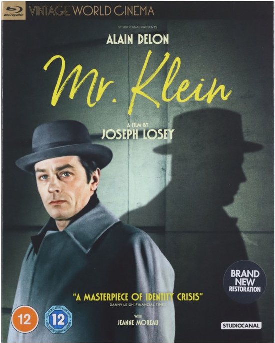 Blu-ray hoes van Mr. Klein, Alain Delon draagt een grijze jas en hoed, met schaduw op de achtergrond.