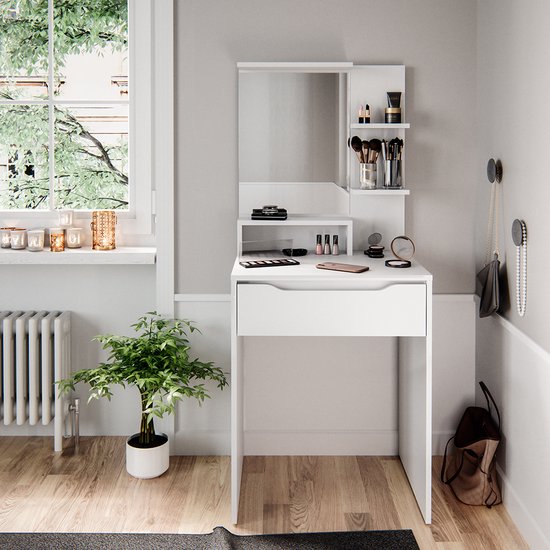 Witte kaptafel met spiegel, diverse make-up producten en een plant ernaast.