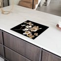 Glazen snijplank met witte en gouden bloemen, geplaatst op een aanrecht.