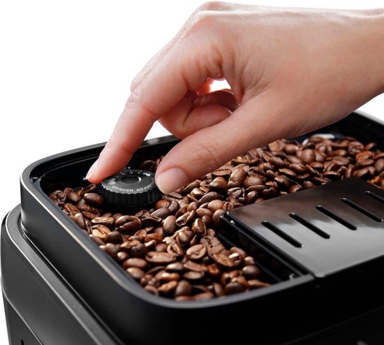 Hand draait aan knop 'Grinder Adjust' in reservoir gevuld met koffiebonen.