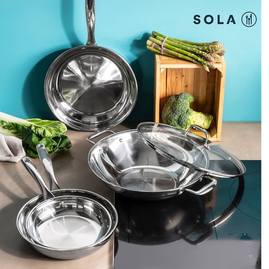 Sola pannen en wok op een kookplaat met groenten, waaronder asperges en broccoli.