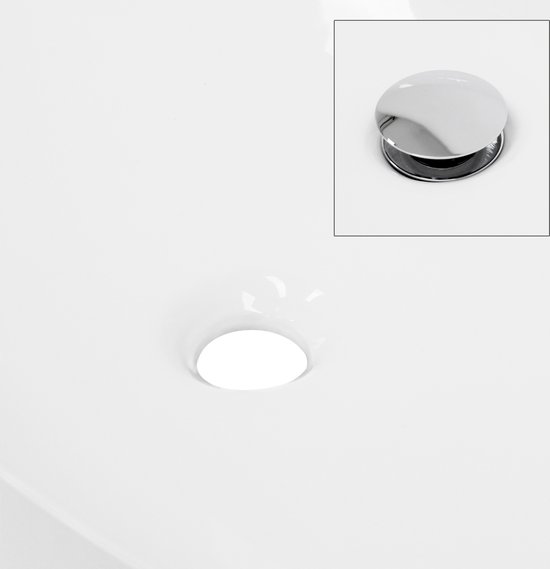 Detail van de ronde afvoer in een witte wastafel.