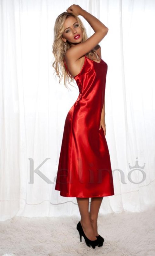 Model in een glanzende, rode satijnen slipdress tot op de kuit, met dunne bandjes. Ze draagt zwarte pumps.