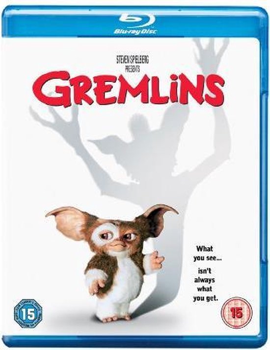 De voorkant van de Blu-ray van Gremlins, met een kleine, pluizige gremlin die naar de kijker kijkt, met een schaduw op de achtergrond.