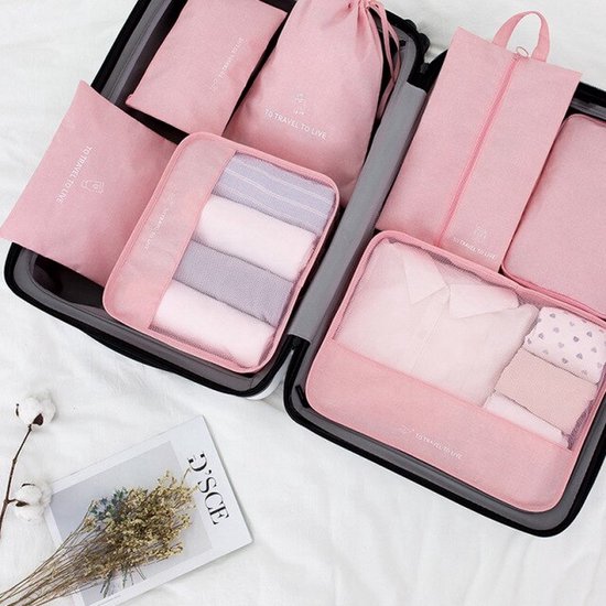 Roze packing cubes met kleding en schoenen in een koffer.