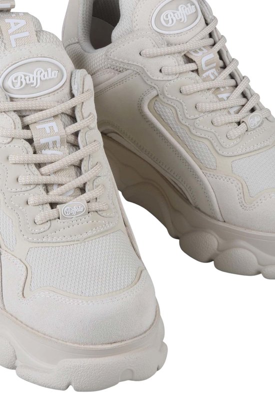 Close-up van lichtbeige Buffalo sneakers. Logo's op de tong en vetersluiting. Mesh en suède details.