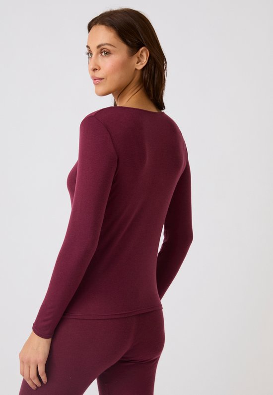 Model van achteren gezien, draagt een bordeauxrode top met lange mouwen en bijpassende legging.
