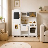 Witte kinderkeuken met gouden details, inclusief magnetron, oven en accessoires, in woonkamer.