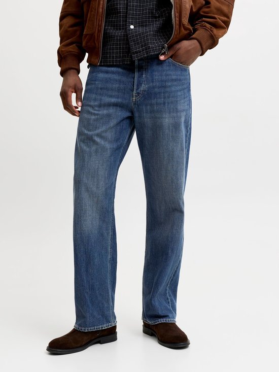 Man draagt een geruite blouse, bruine jas en wijde blauwe jeans.