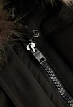 Detail van de metalen rits met Superdry-logo op een zwarte jas met bontkraag.
