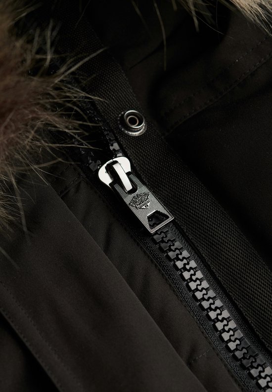 Detail van de metalen rits met Superdry-logo op een zwarte jas met bontkraag.