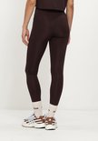 Achterkant van een bruine legging met een wit Adidas-logo op de linkerheup.