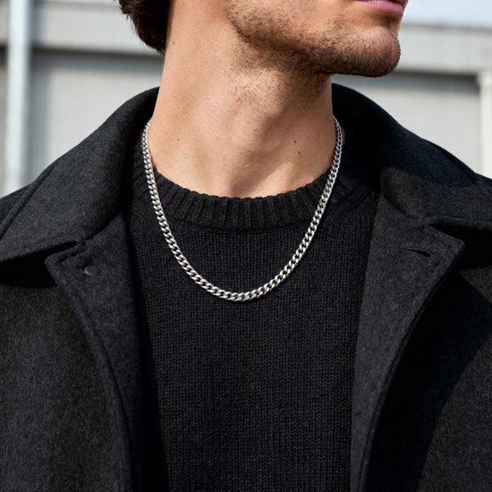 Man met zilverkleurige schakelketting van 6 mm, gedragen met een zwarte coltrui en jas.
