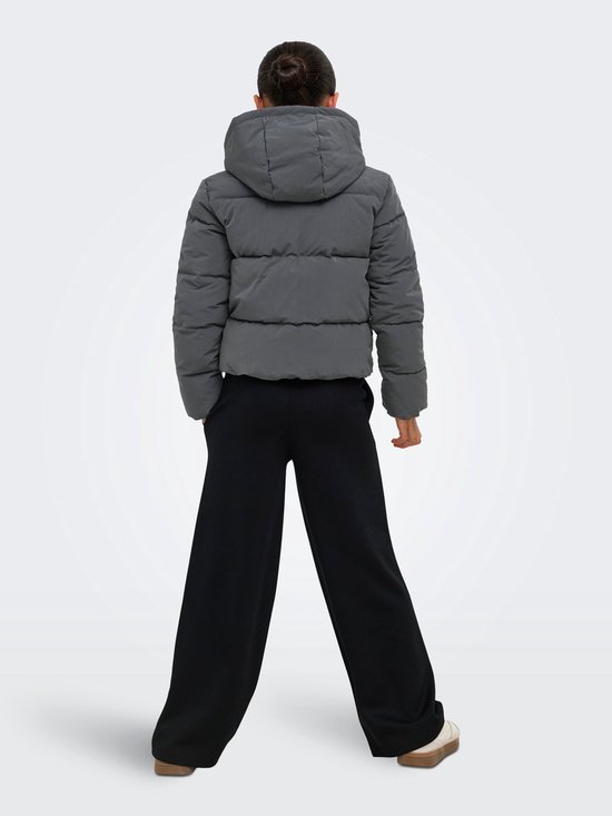 Model van achteren gezien in een grijze, korte pufferjack met capuchon en zwarte broek.