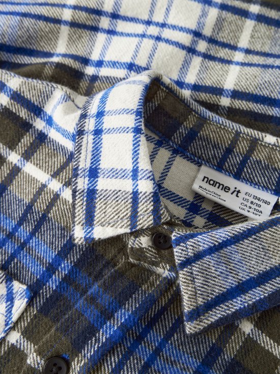 Detailopname van de kraag en het label van een blauw, wit en olijfgroen geruit overshirt van Name it.