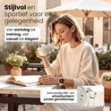 Een vrouw met een crème smartwatch op haar pols, genietend van een kopje koffie bij een open boek.
