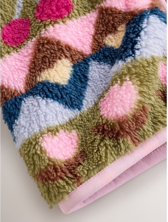Close-up van de boord van een fleece babyjasje met een patroon van harten en driehoeken in roze en groen.