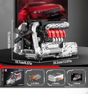 Gedetailleerd V8 motor model met zilveren en rode accenten, met afmetingen aangegeven. De doos toont het model en de meegeleverde motor, batterij en handleiding.