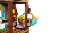 Bruine LEGO-hond met groene pet zit in een LEGO-stoeltjeslift, met pastelkleurige LEGO-elementen en sterren.