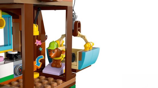 Bruine LEGO-hond met groene pet zit in een LEGO-stoeltjeslift, met pastelkleurige LEGO-elementen en sterren.