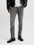 Detail van grijze jeans met zwarte laarzen.