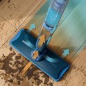 Blauwe dweilkop met waterreservoir dat water spuit tijdens het schoonmaken.