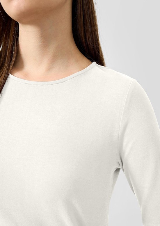 Close-up van de halslijn en schouder van een wit longsleeve shirt van zachte katoen.