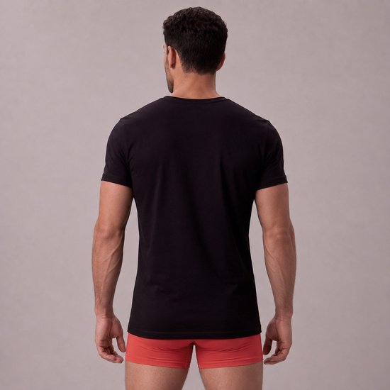 Zwart slim fit V-hals T-shirt van bamboe, achterkant zichtbaar, gedragen door een man met oranje ondergoed.