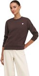 Model draagt bruine sweater met witte hart-applicatie, gecombineerd met witte broek.