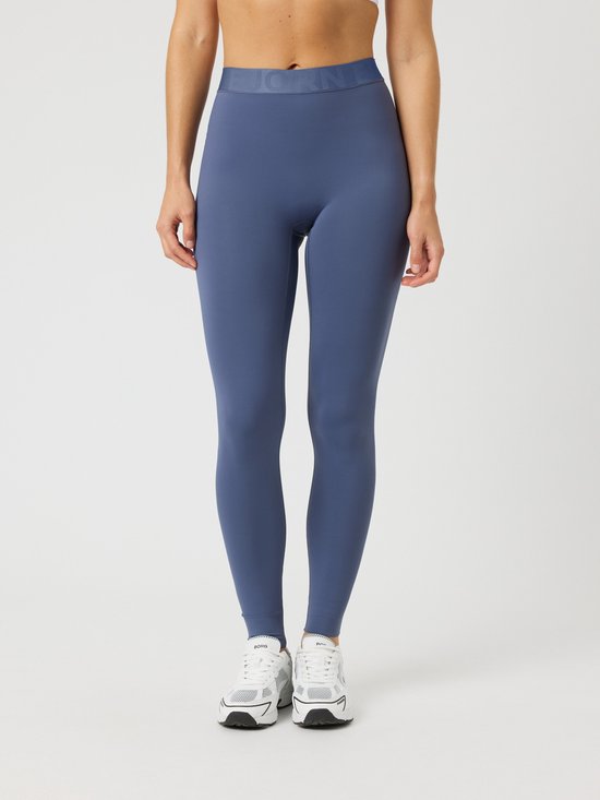 Model draagt een blauwe sportlegging en witte sportschoenen.