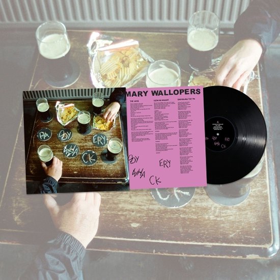 Een vinylplaat met de titel 'Mary Wallopers' op een tafel met glazen bier en chips. Tekst op de hoes: 'Paddywhackery'.