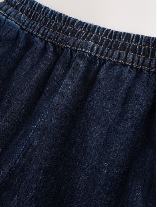 Close-up van de elastische tailleband van een donkerblauwe jeans.