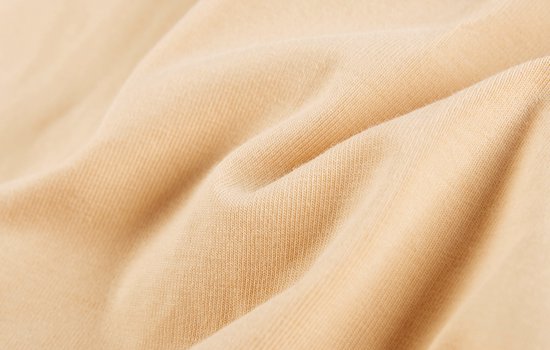 Gedetailleerde close-up van de textuur van beige stof.
