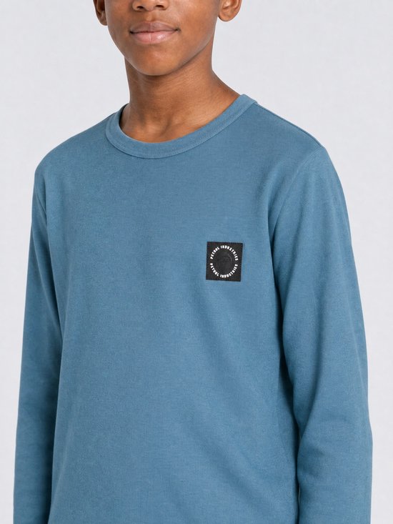 Close-up van jongen in blauw longsleeve T-shirt met borstlogo.