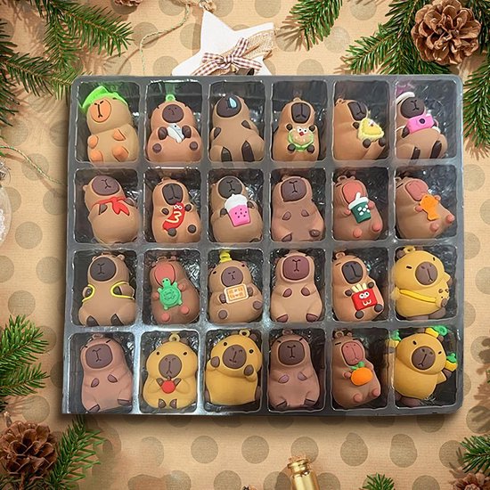 Doos met 24 kleine capybara speeltjes in kerstthema, in rijen gerangschikt.