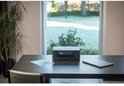 Zwarte Brother multifunctionele printer op een donker houten bureau met briefpapier en een laptop.