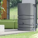 Grijze regenwatertank met 5 ribbels, staand naast een groene loungebank.