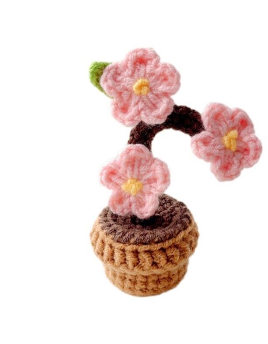 Handgeweven bloemen worden in gehaakte bloempotten geplant.