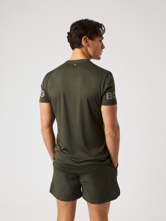 Man met korte mouwen, donkergroen sportshirt met grijze logo opdruk op de mouwen.