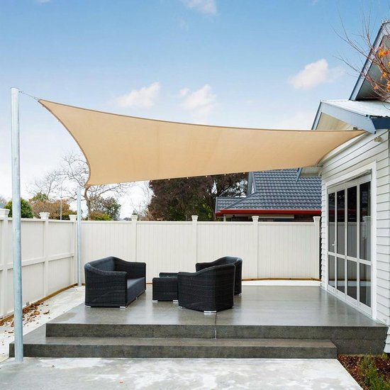 Beige rechthoekig schaduwzeil boven een terras met zwarte tuinmeubelen bij een wit huis.