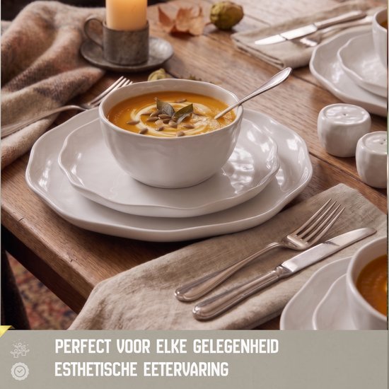 Witte borden en kommen met een golvend profiel, gedekt voor een herfstig diner met pompoensoep.