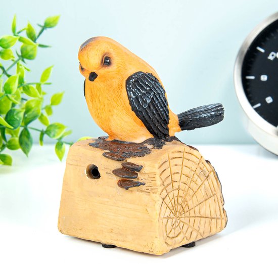 Oranje vogeldecoratie op een houten blok met zwarte vleugels.