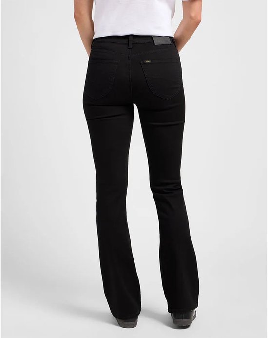 Model van achteren gezien in zwarte flared jeans met een wit T-shirt en donkere sneakers.