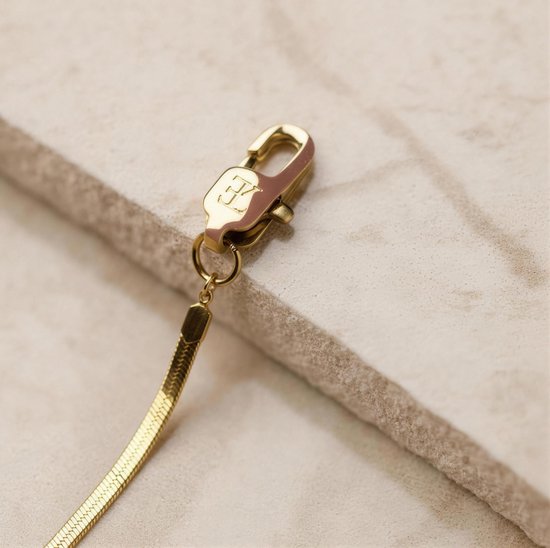 Sluiting van gouden slangenketting met een karabijnsluiting en gegraveerd logo.